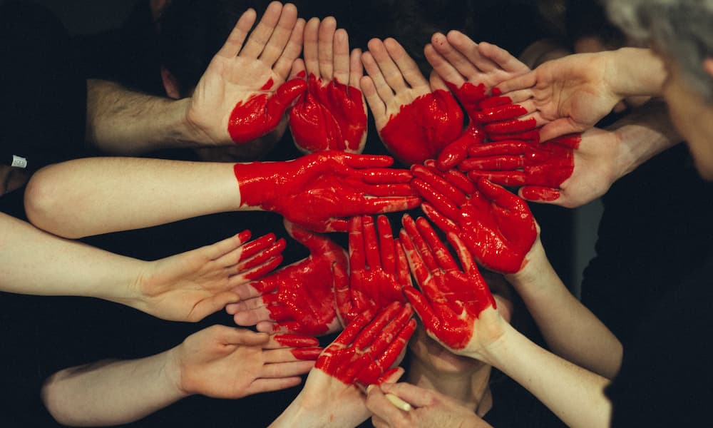 Hands together with a red heart painted of the grouped hands